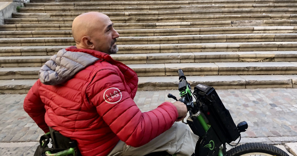 Hombre el silla de ruedas frente a escaleras